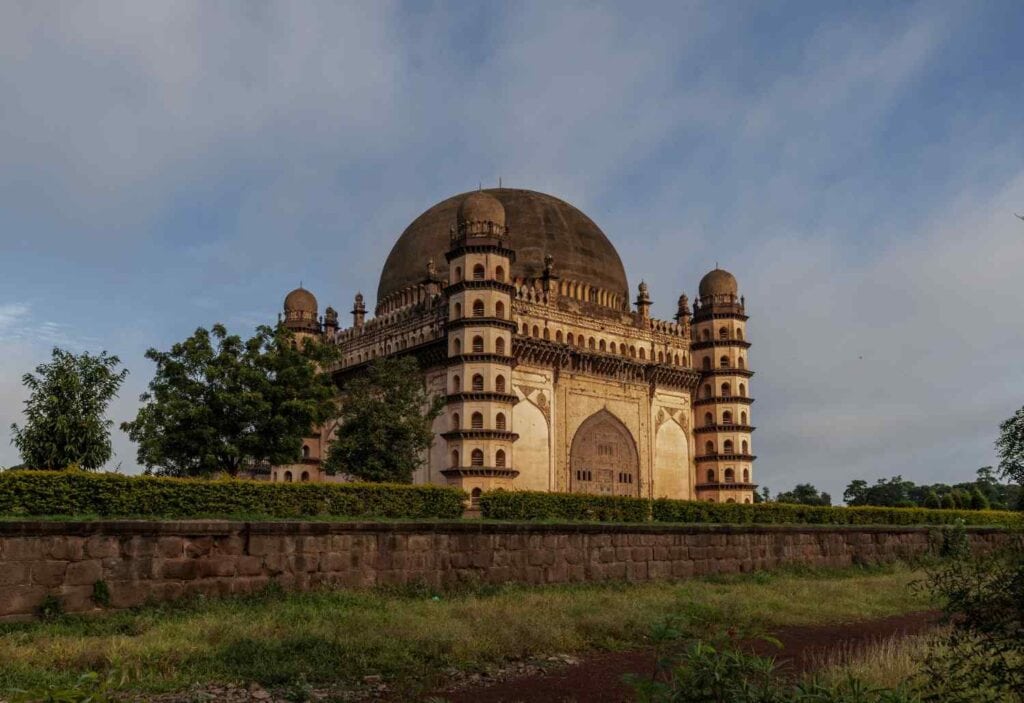 The grand Gol Gumbaz monument in Vijayapura, Karnataka, showcasing its iconic massive central dome against a clear sky.