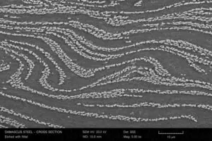 Scanning electron microscope image of Damascus steel cross-section showing iron carbide cementite banding pattern that John Verhoeven identified at Iowa State University in 1998 reconstructing Wootz formula